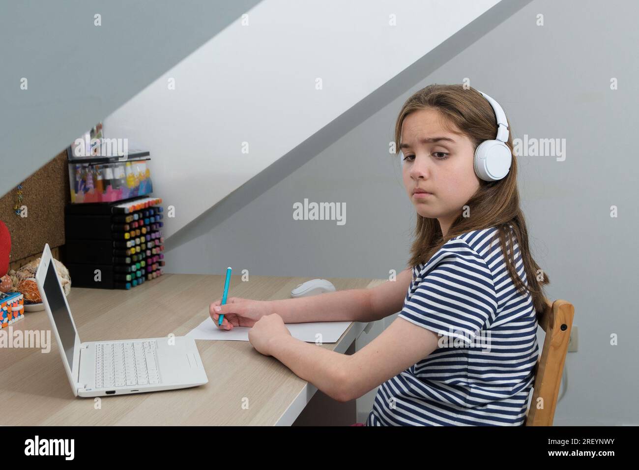 The girl is experiencing discomfort while doing homework. Strange sounds from outside, Someone is calling Stock Photo