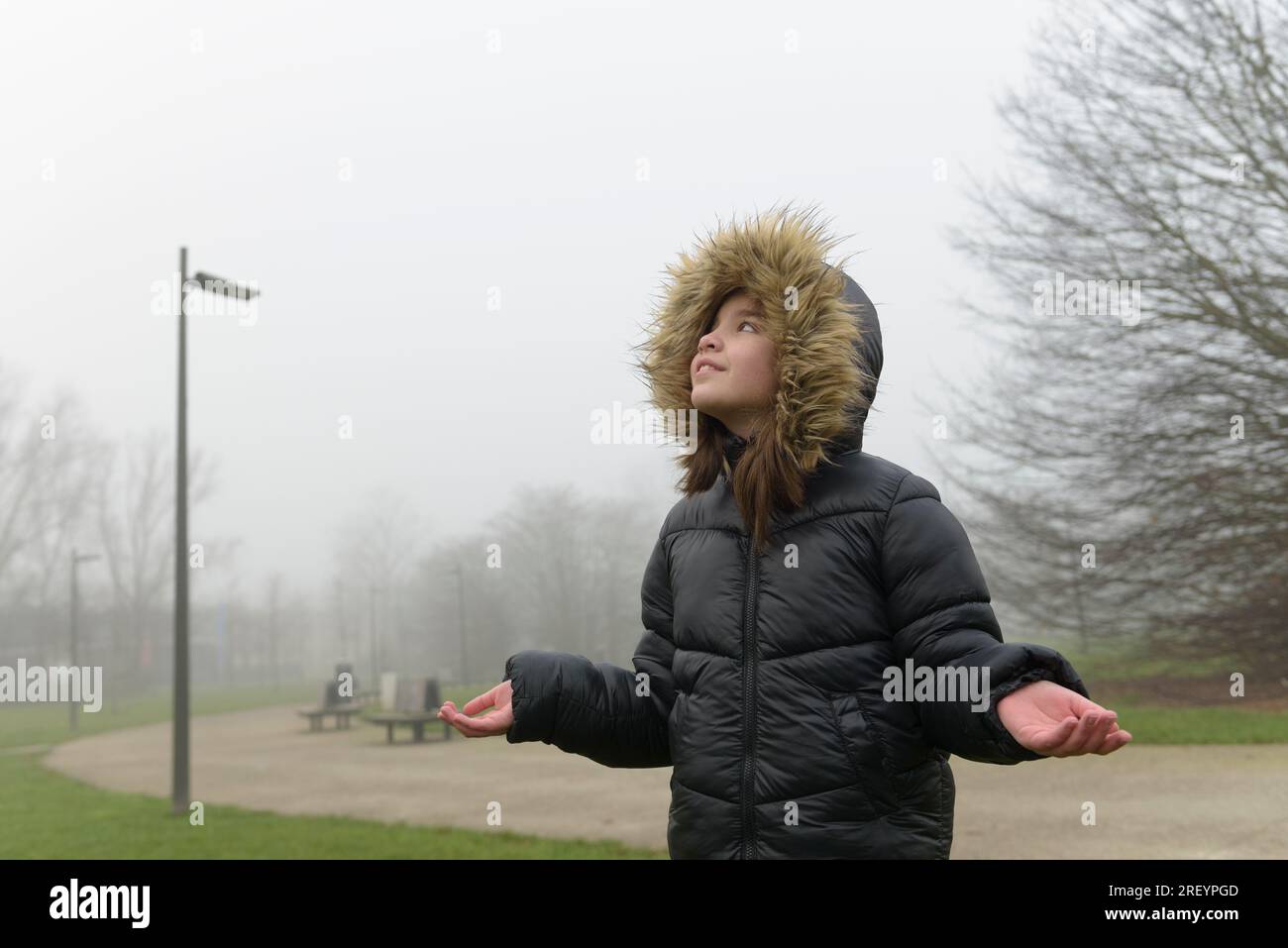Waiting for snow. Portrait of a girl in cold weather in a warm jacket with a fur hood. Place for text Stock Photo