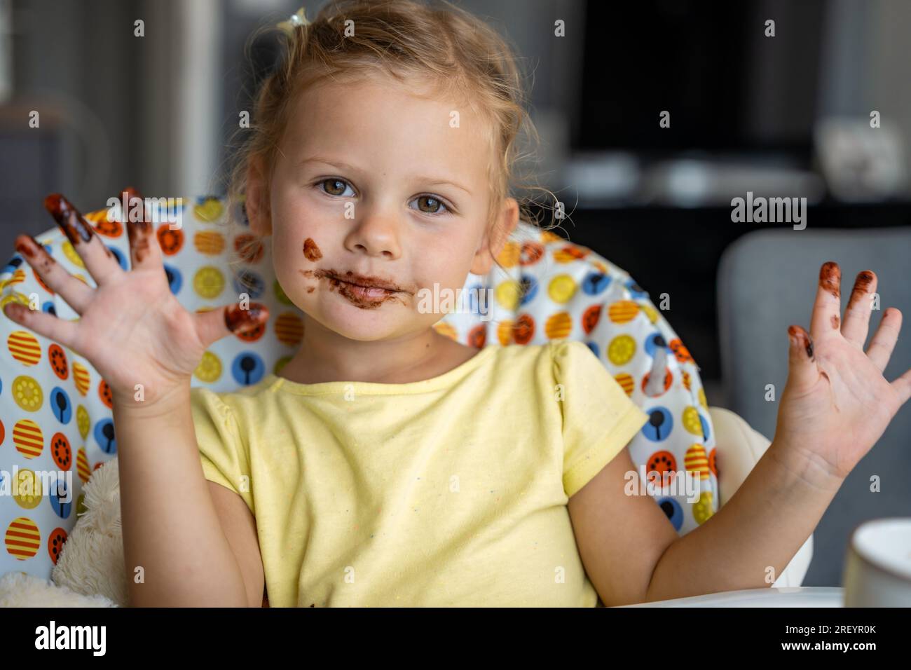Little girl with blond hair eating homemade chocolate and showing mouth