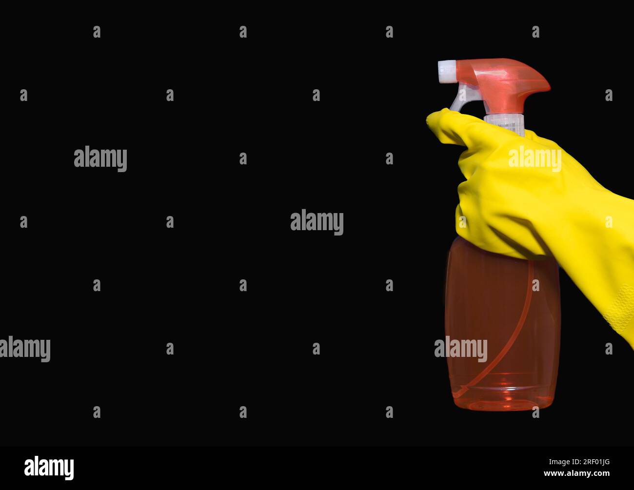 Hand in yellow rubber gloves with a container of detergent. close up ...