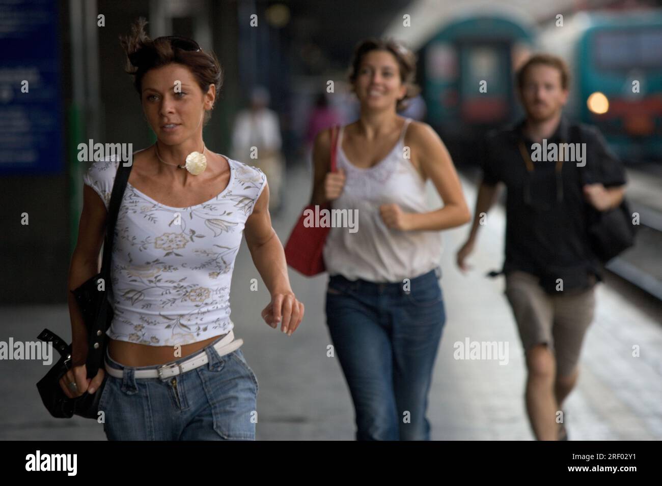 Three people running along a train platform, with a train visible in ...