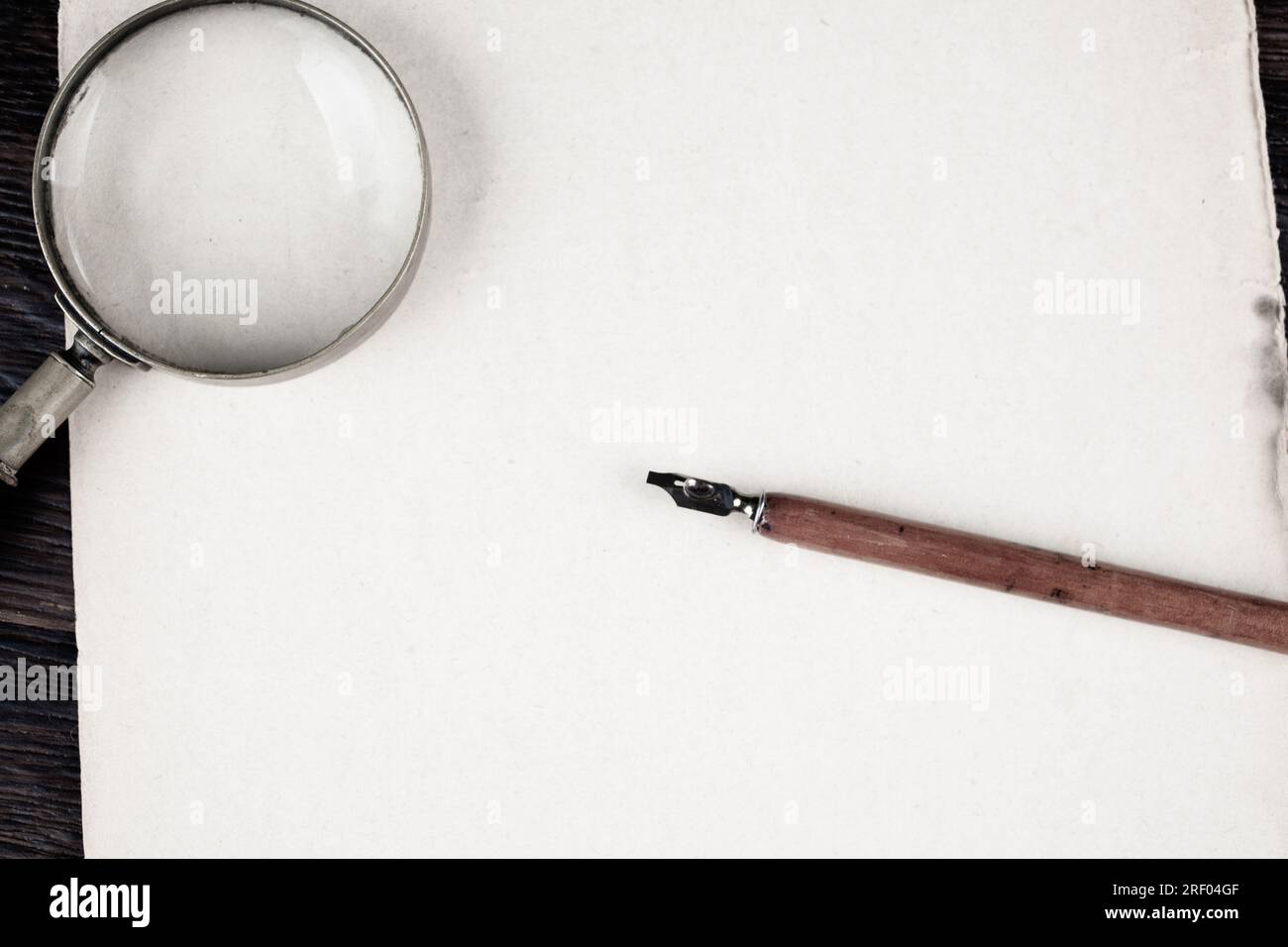 Magnifying glass with old ink feather pen on paper background Stock ...