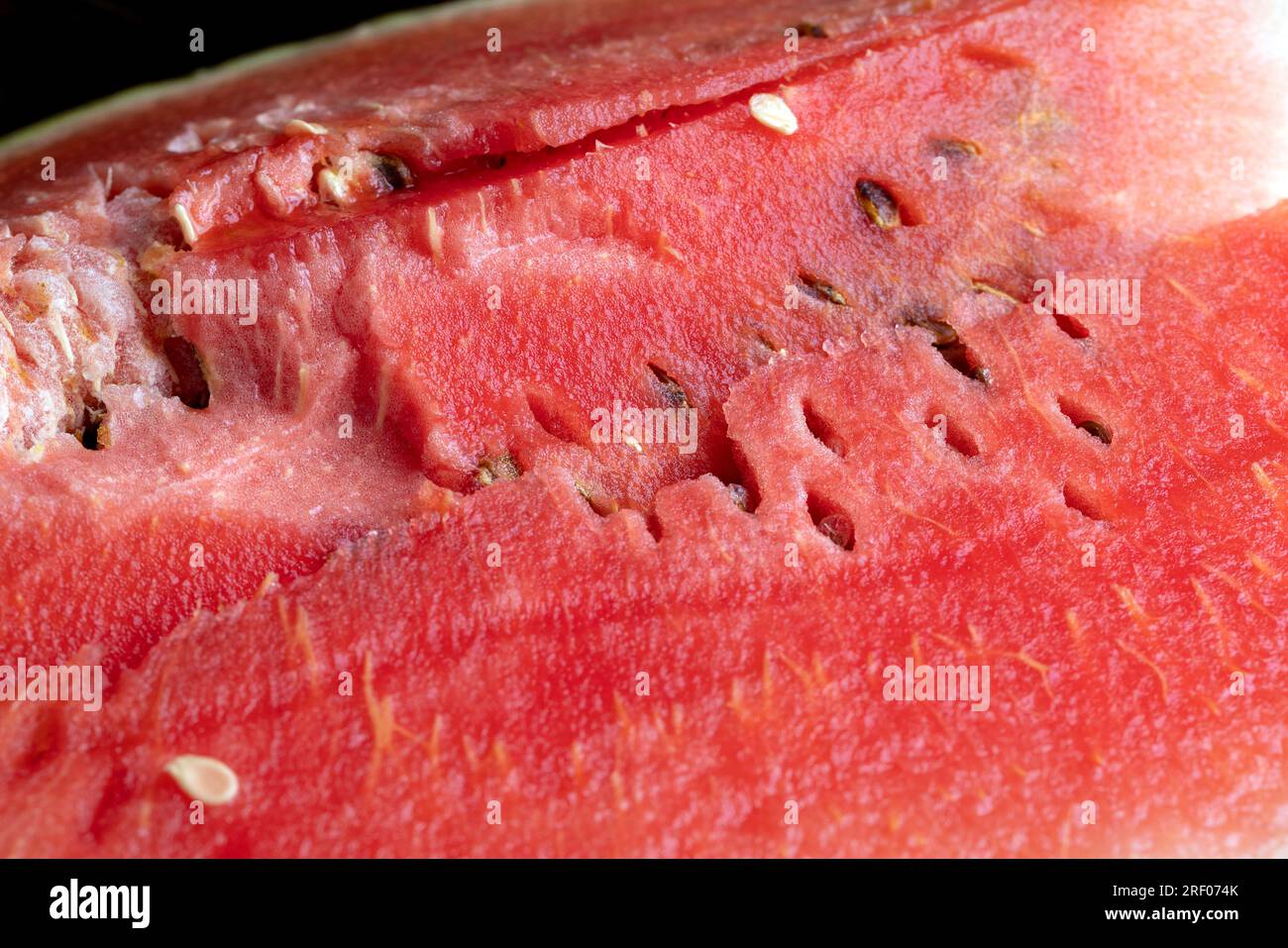 Unripe watermelon pink with black seeds, broken and cut into pieces
