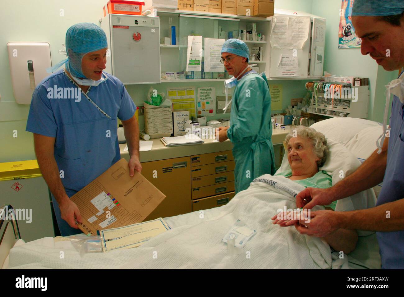 Healthcare professionals attending to an elderly patient in a hospital setting. Stock Photo