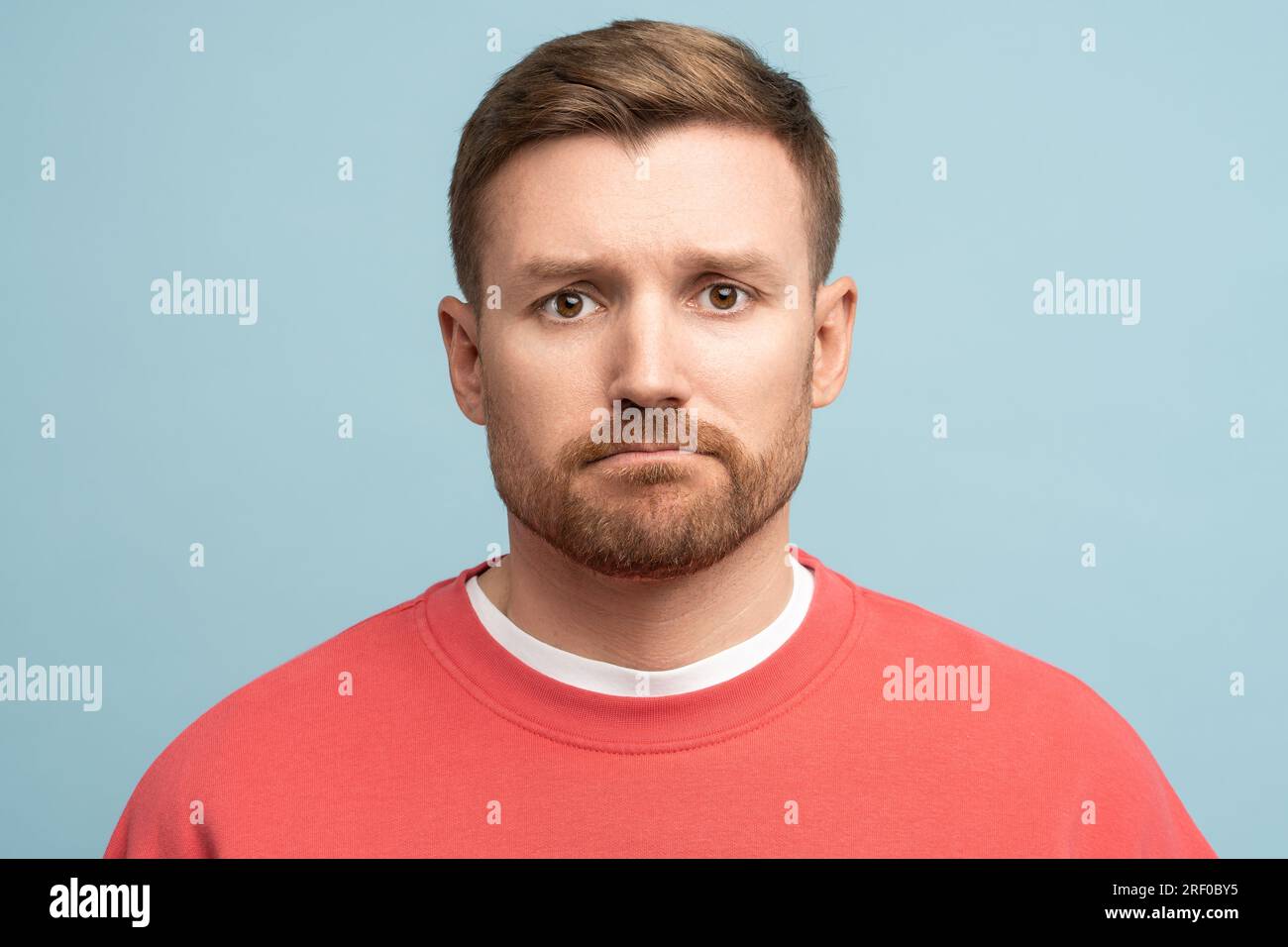 Portrait of middle aged sad confused frustrated man with pursed lips in trouble on blue background. Stock Photo