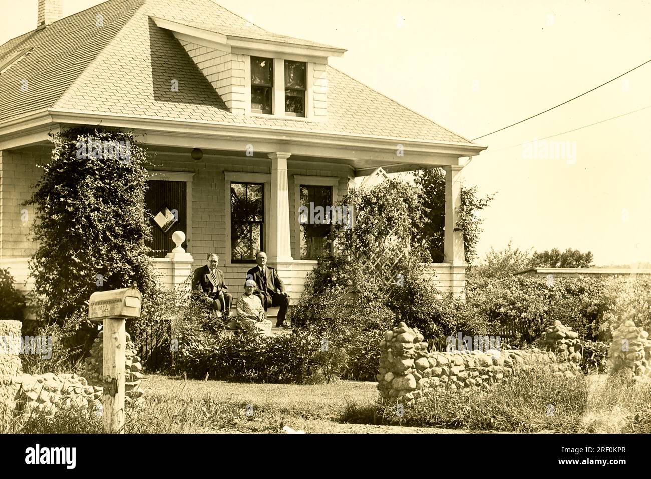 Farmhouse on Plainville Road in New Bedford. This photo dates to around 1915 and shows a house on a farm in the northend of New Bedford; Massachusetts. The owner is the man at right; and two. of his children are with him. The area was called Plainville; and the location of the house was Plainville Road. Stock Photo