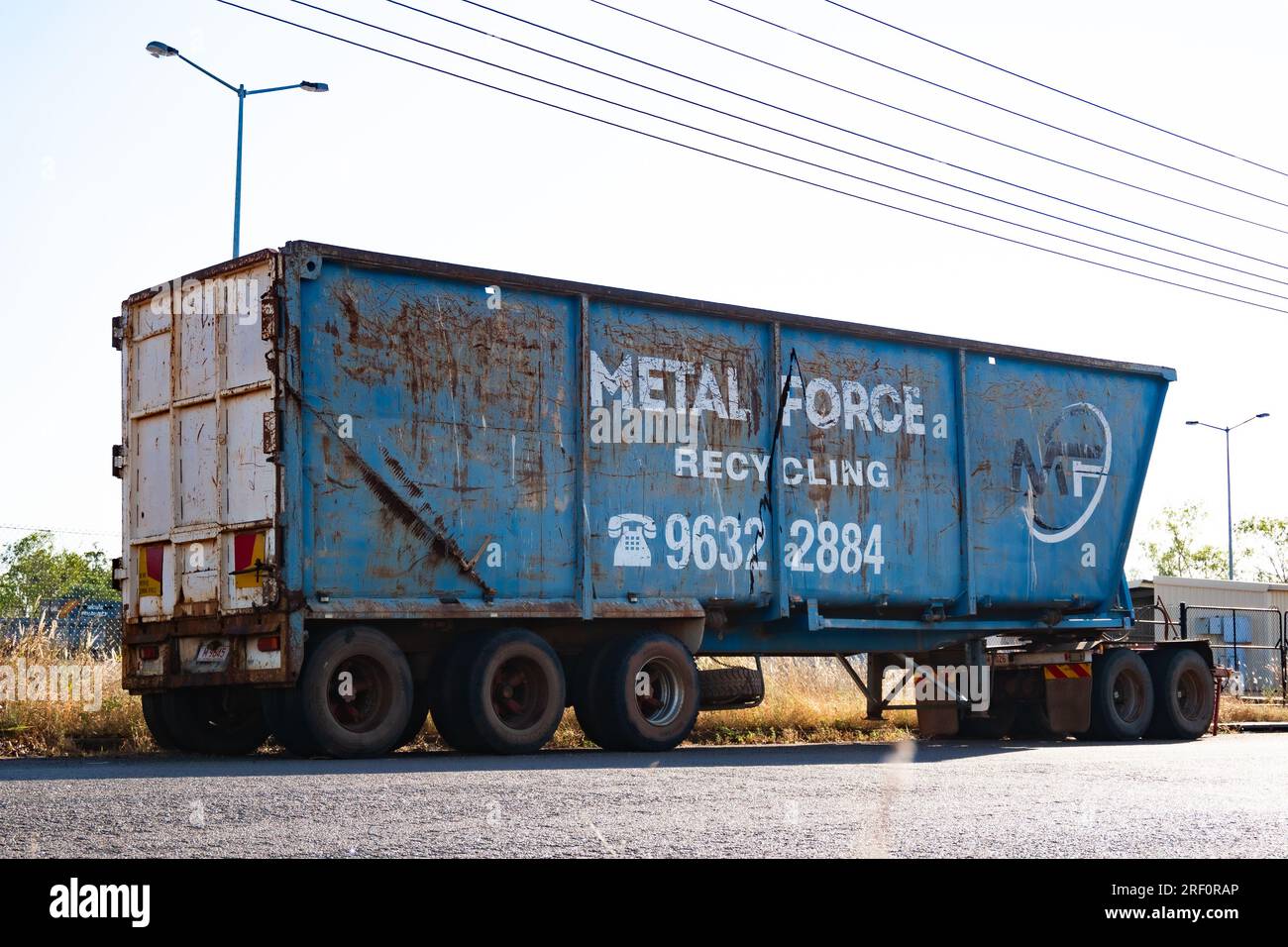 A blue and well worn large metals recycling bin awaits a new load of scrap atop an 18 wheeler truck trailer. Stock Photo