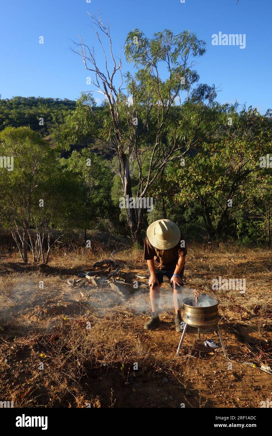 Checking on the firepit, evening campsite in the bush near Laura, southern Cape York Peninsula, Queensland, Australia. No MR Stock Photo