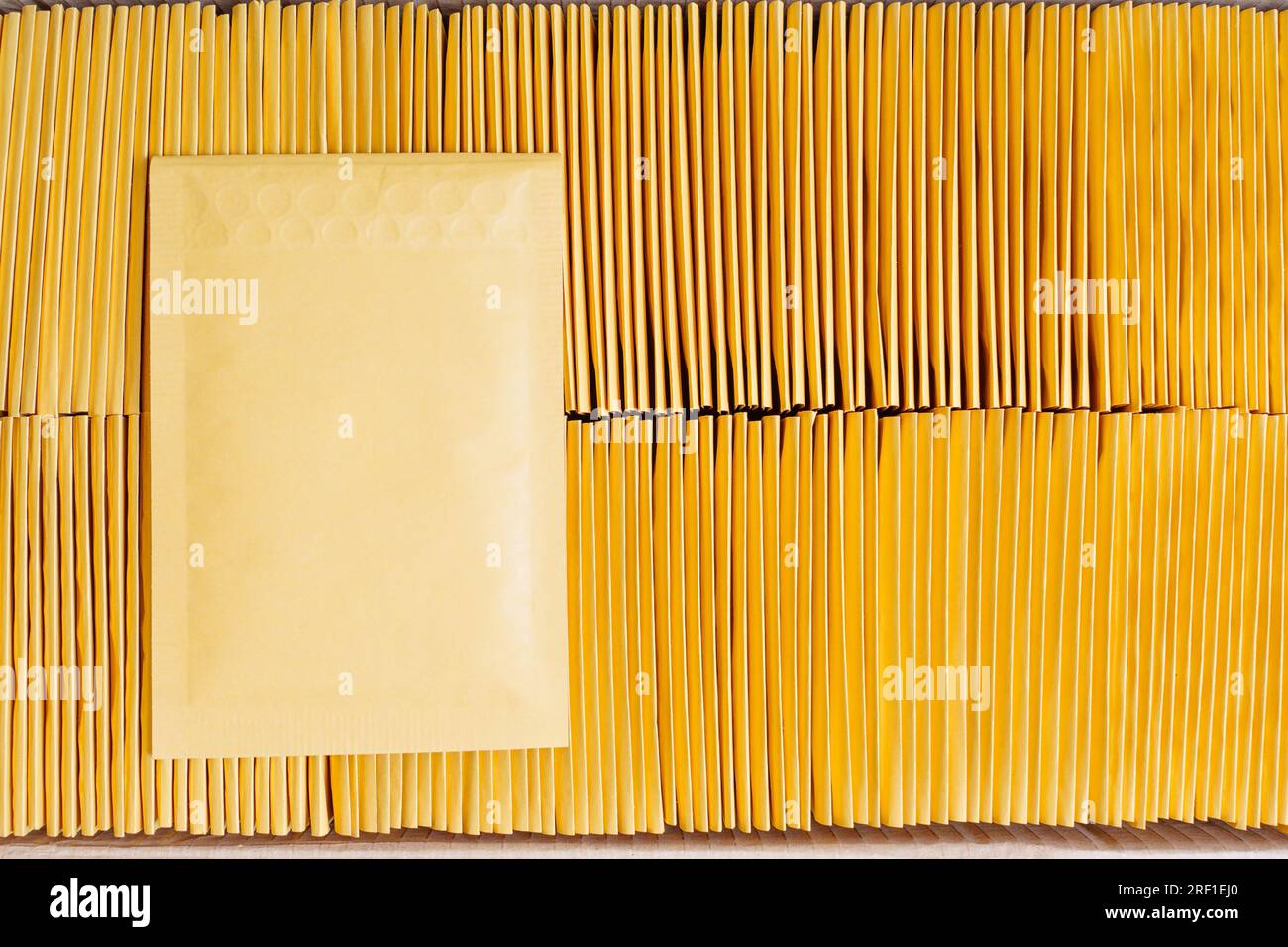 Closeup of a shipping cardboard box filled with padded envelopes and one yellow mailer placed