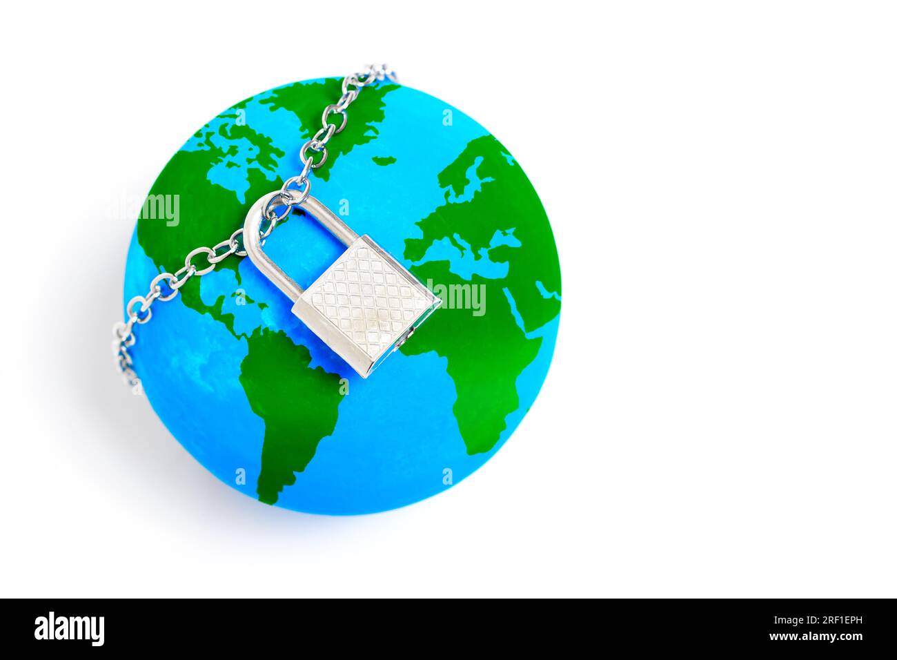 Miniature globe secured with a chained padlock, symbolizing the confinement and restrictions imposed on the interconnected world. Global challenges, h Stock Photo