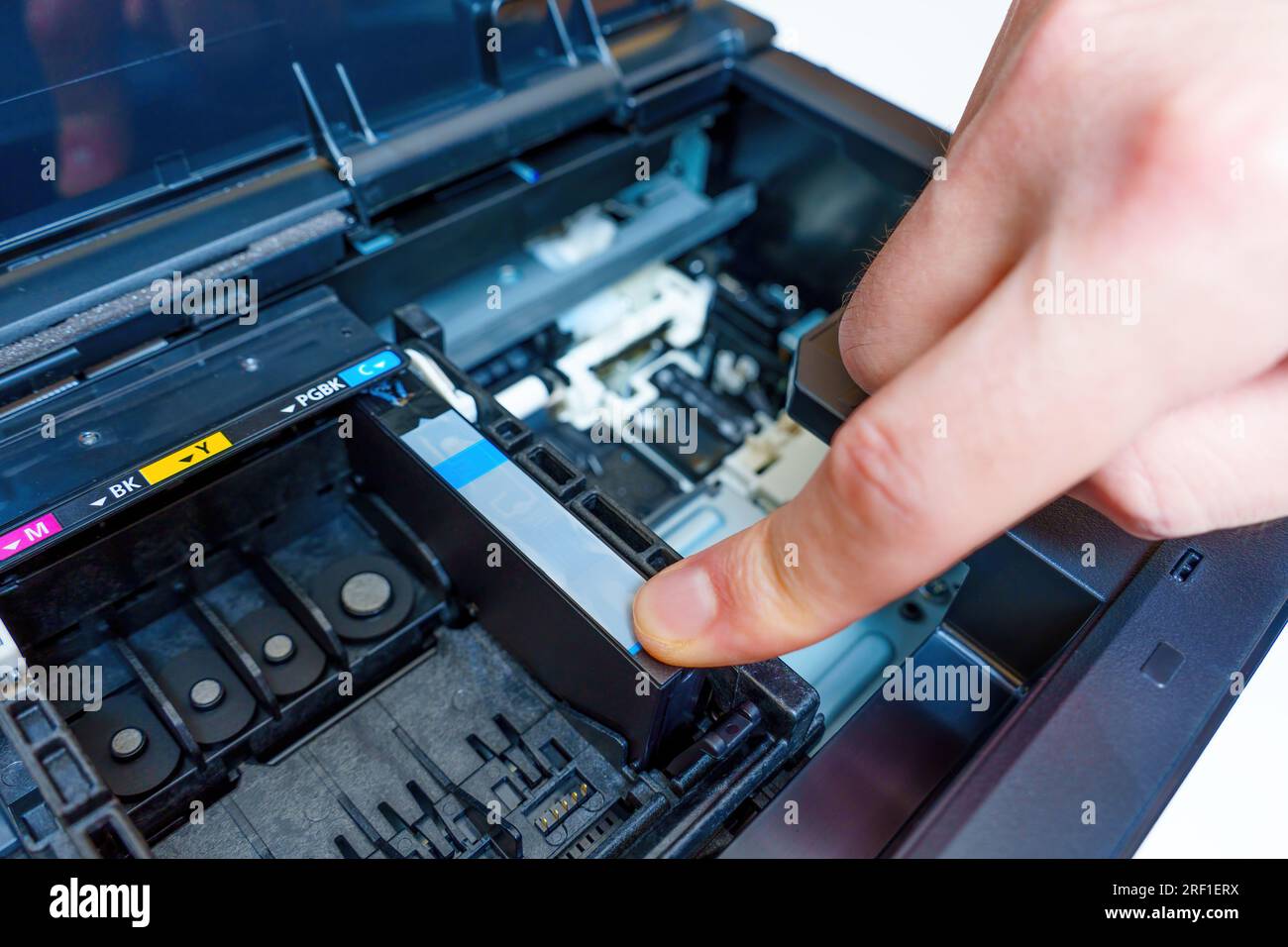 Hand inserts a fresh ink cartridge into the carriage of the inkjet printer Stock Photo Alamy