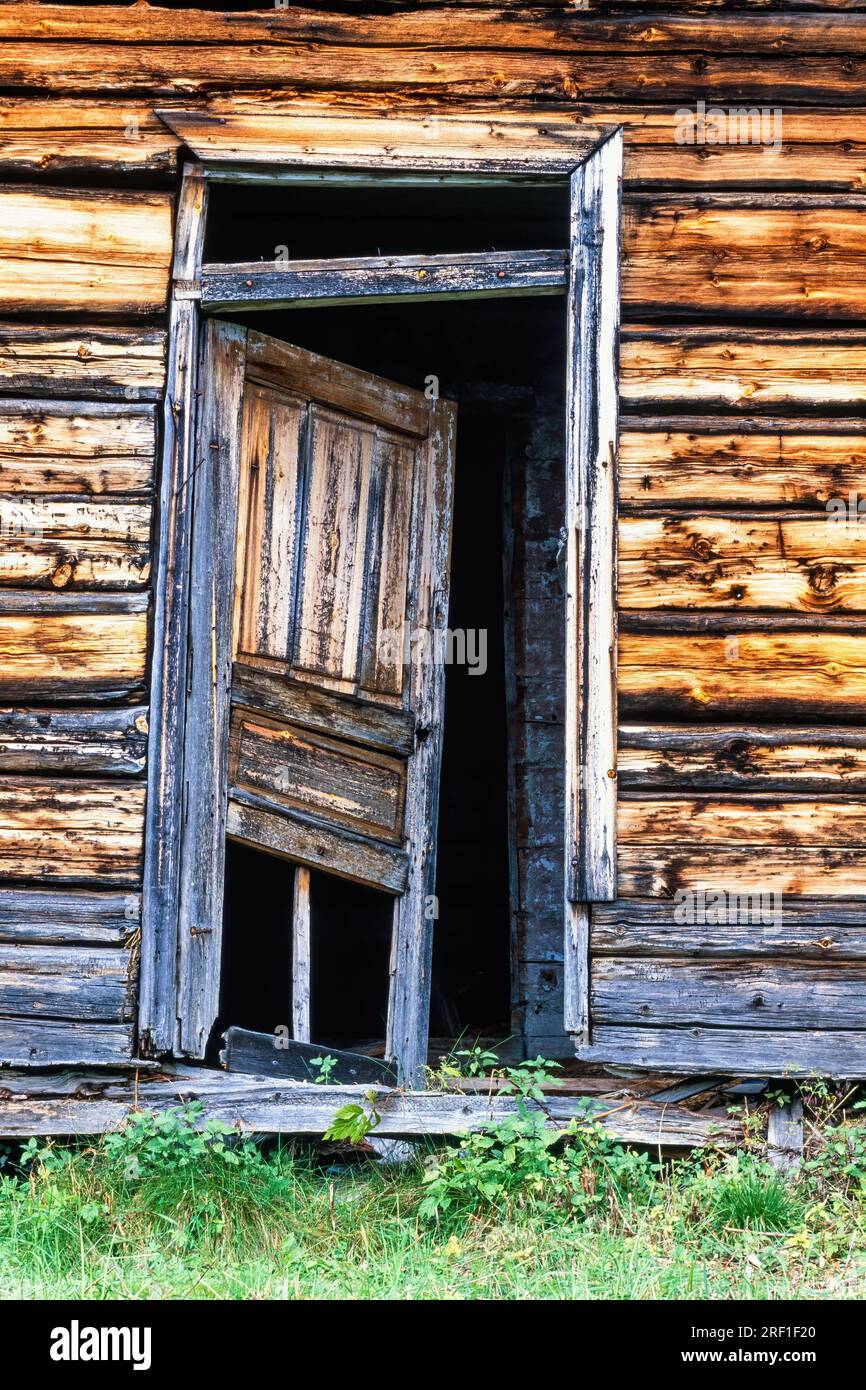 Abandoned old log house with a broken door Stock Photo