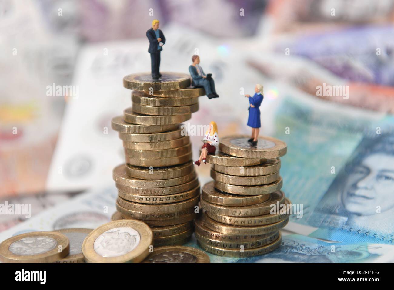 Undated file photo of models of men and women on a pile of coins and bank notes. A new consumer duty has come into force, setting a higher bar for financial firms and giving customers more certainty that the product they are taking out does exactly 'what it says on the tin'. Overseen by the Financial Conduct Authority (FCA), it sets higher and clearer standards of consumer protection across financial services, requiring firms to put customers' needs at the heart of what they do. Issue date: Monday July 31, 2023. Stock Photo