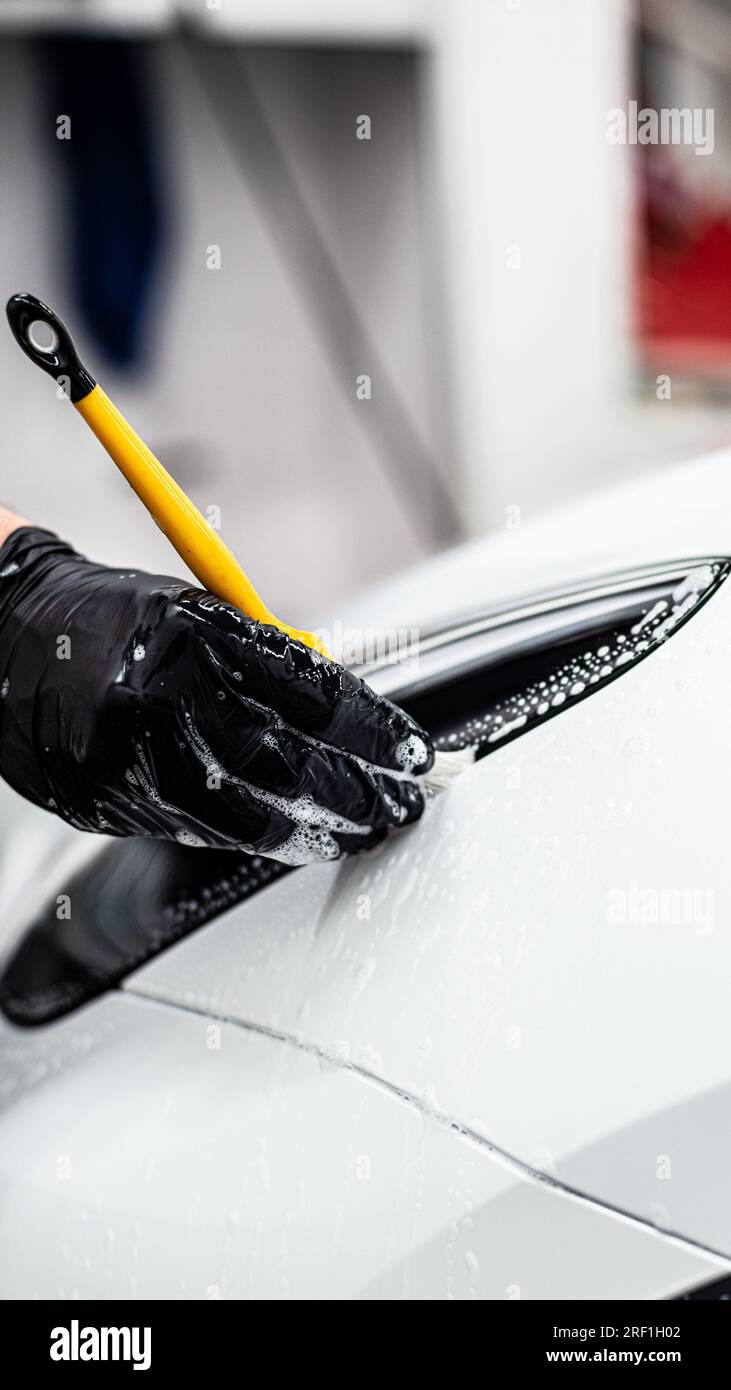 Employee of a car detailing studio or car wash carefully cleans the