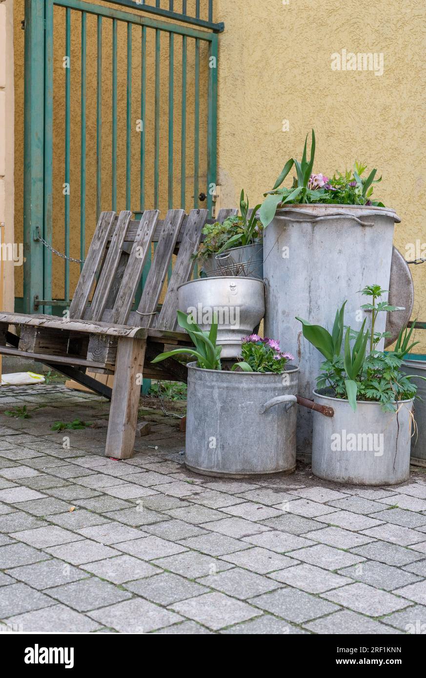 Garbage can and zinc pot planted with flowers Stock Photo