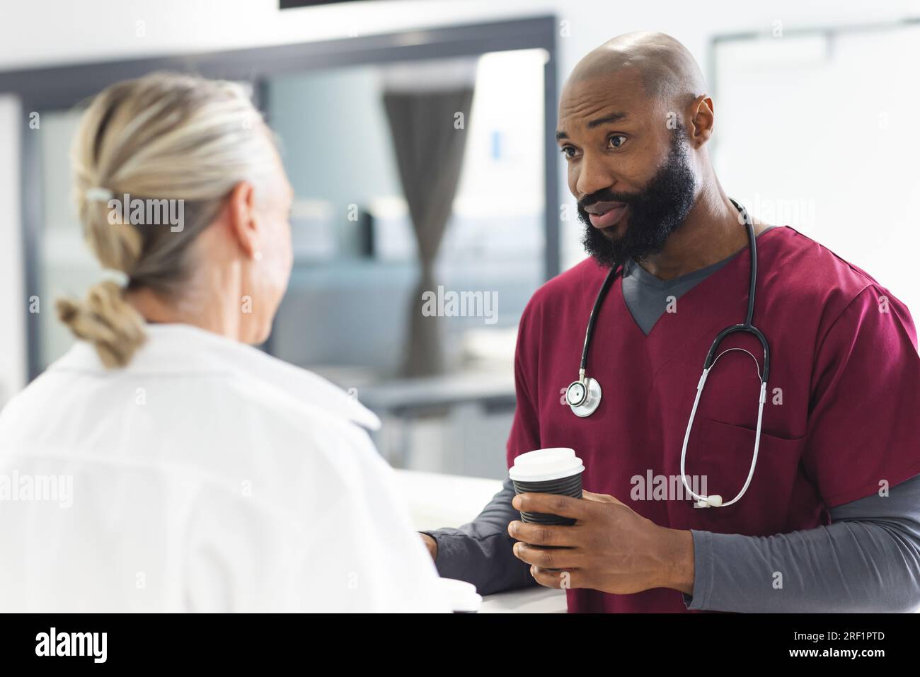 Diverse male and female doctors talking and drinking coffee in