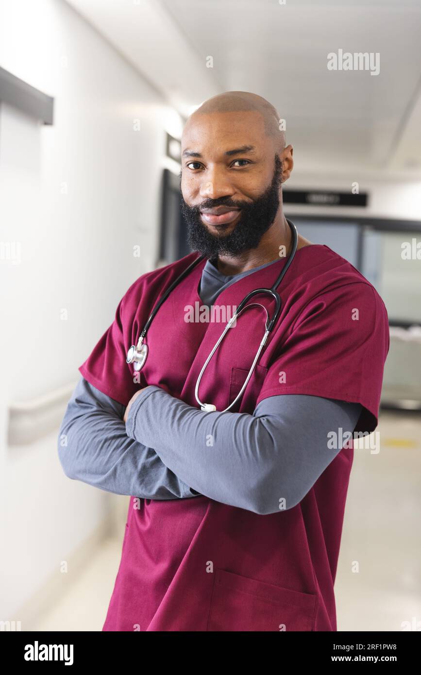 Portrait of happy african american male doctor wearing red scrubs in