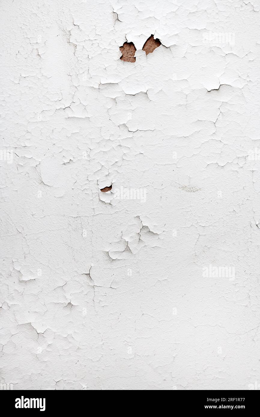 Old wall with white paint peeling off the surface as grunge background and texture, vertical image Stock Photo