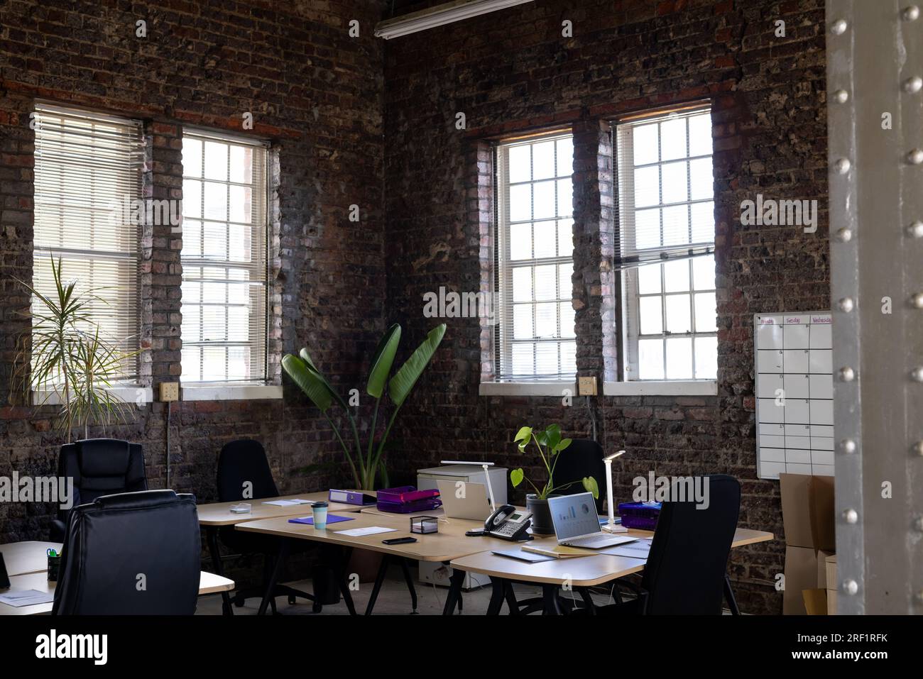 Modern casual office interior with exposed brick walls, desks and chairs Stock Photo