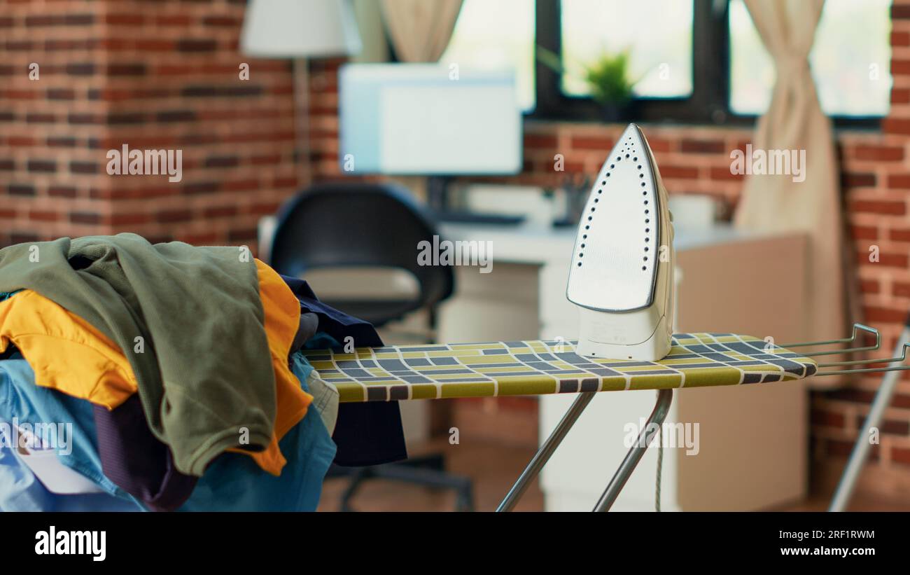 Empty household with iron and ironing table, big pile of washed clothes