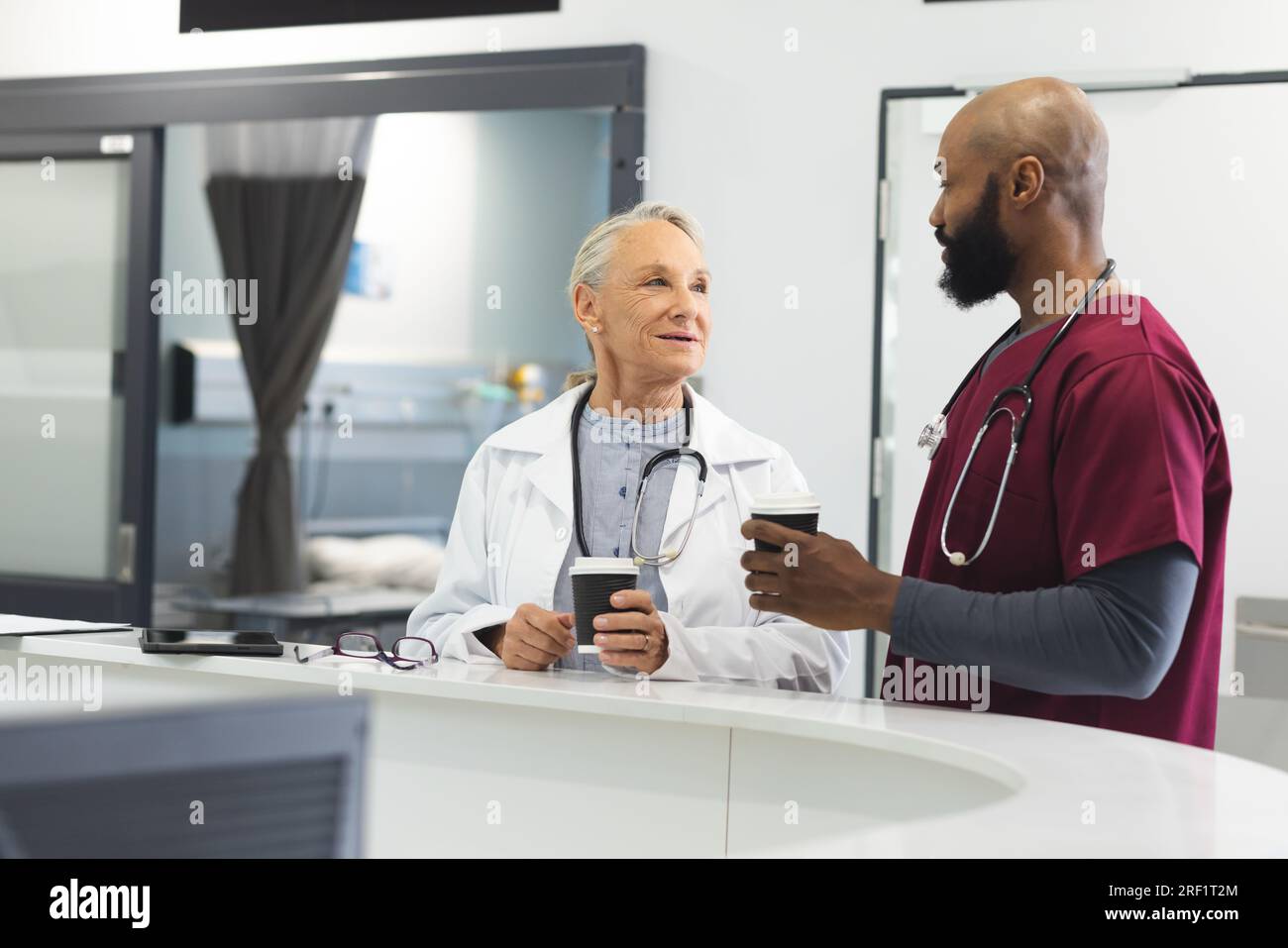 Diverse male and female doctors talking and drinking coffee in