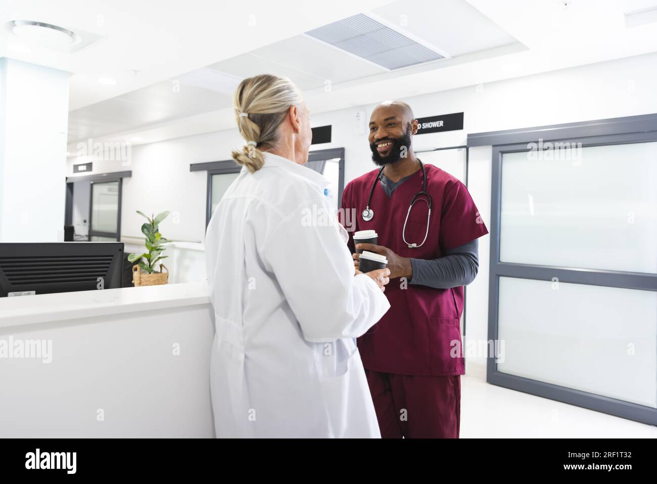 Diverse male and female doctors talking and drinking coffee in