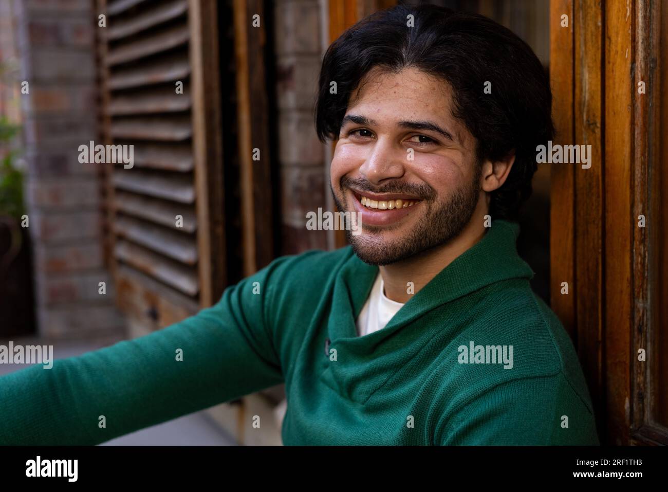 Portrait of happy indian man sitting by window outside house Stock ...