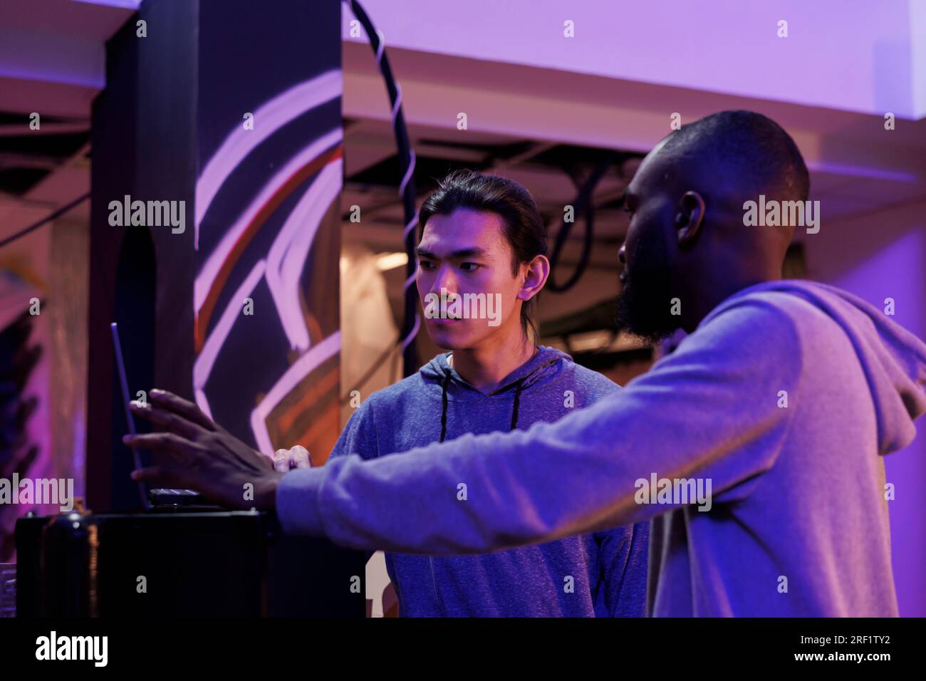Criminals discussing hacking plan while analyzing malware code on laptop. Two hackers talking about password cracking malicious software to break into database online server Stock Photo