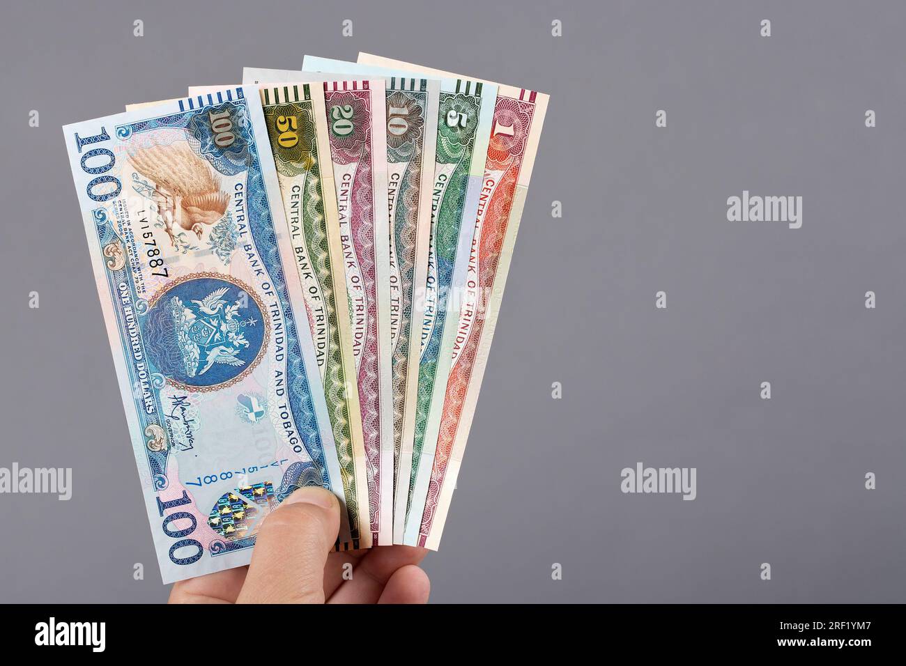Old Trinidad and Tobago money dollar in the hand on a gray background