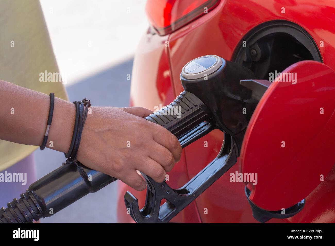 the driver's hand takes the nozzle of the gas pump in the oil tank, refills the fuel gas in the oil tank for self-service during the trip Stock Photo