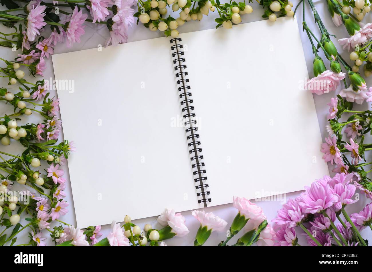 Empty white notebook and pencil with pink flowers on white background. Stock Photo