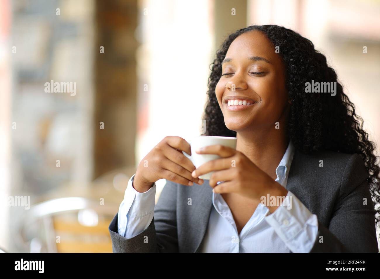 Happy black executive breathing in a coffee shop terrace Stock Photo