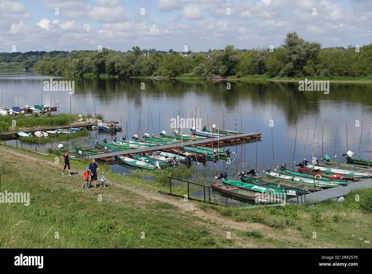 A familly walking by fishing boats in the small river port of Nowy Dwor Mazowiecki, Poland, on the Narew River Stock Photo