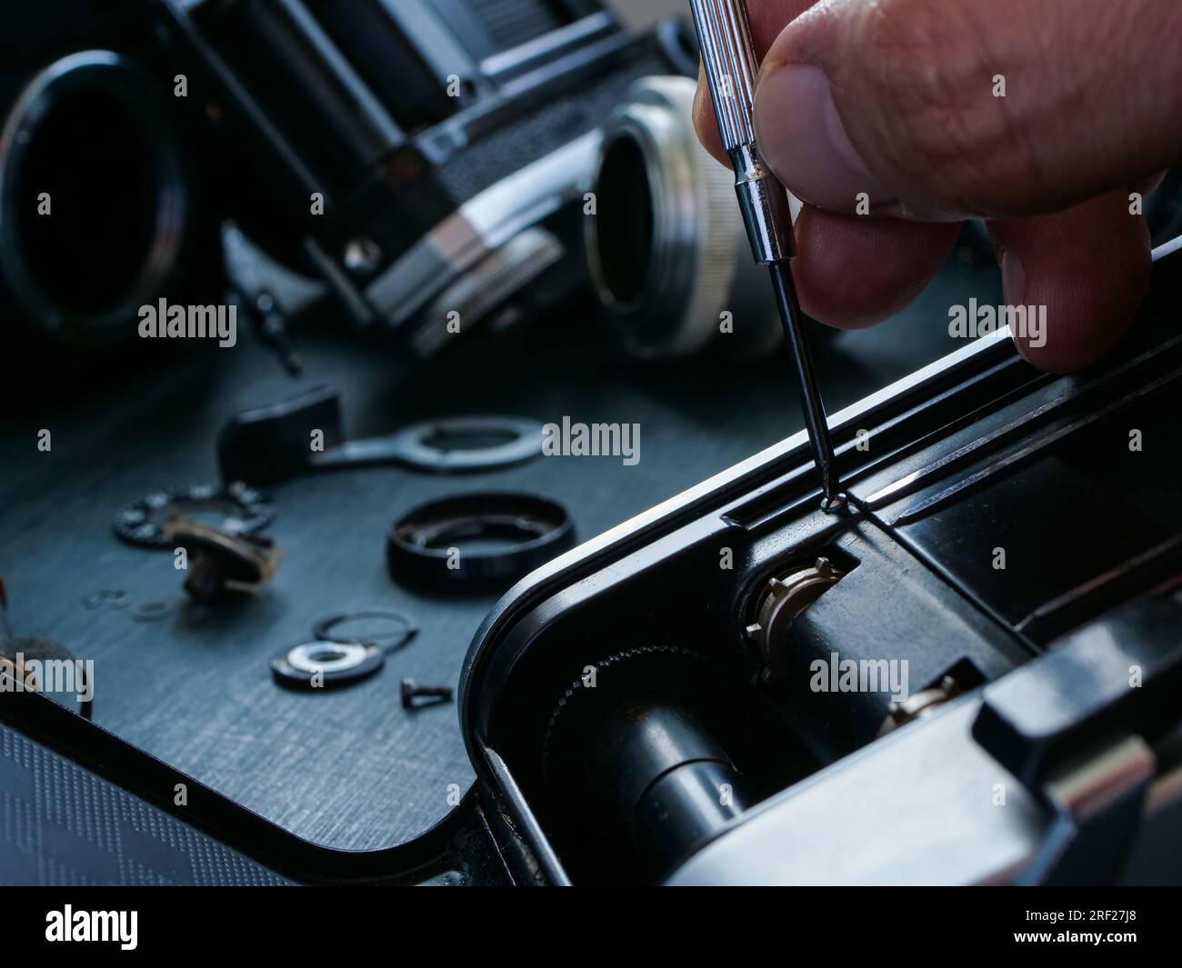 Close-up of hand with a screwdriver repairing an old film camera. Stock Photo