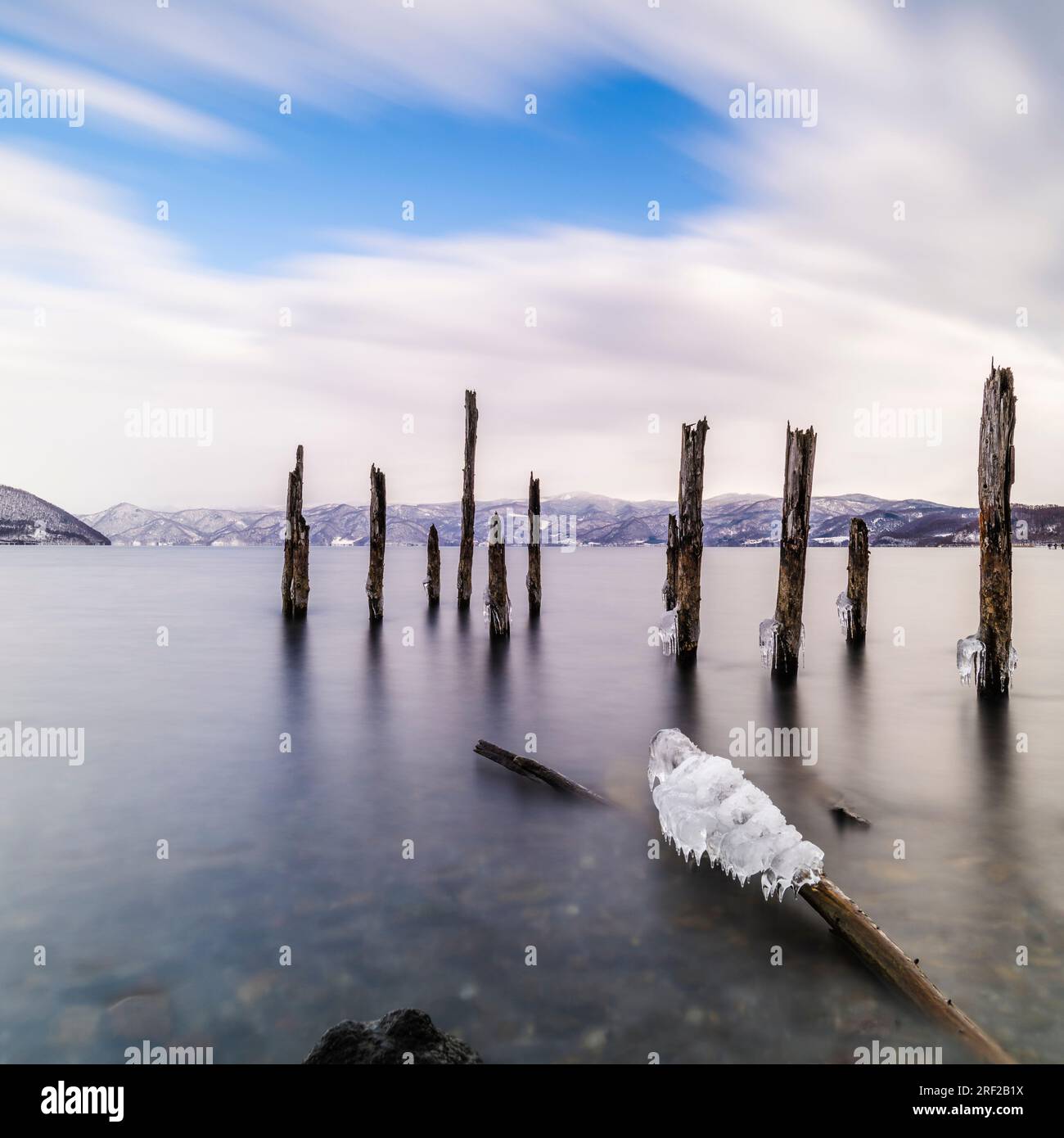 Long exposure shot of wooden sticks in the water at lake Toya, Hokkaido, Japan Stock Photo