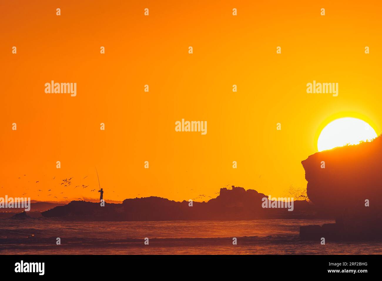 Man Fishing as the sun is setting Stock Photo