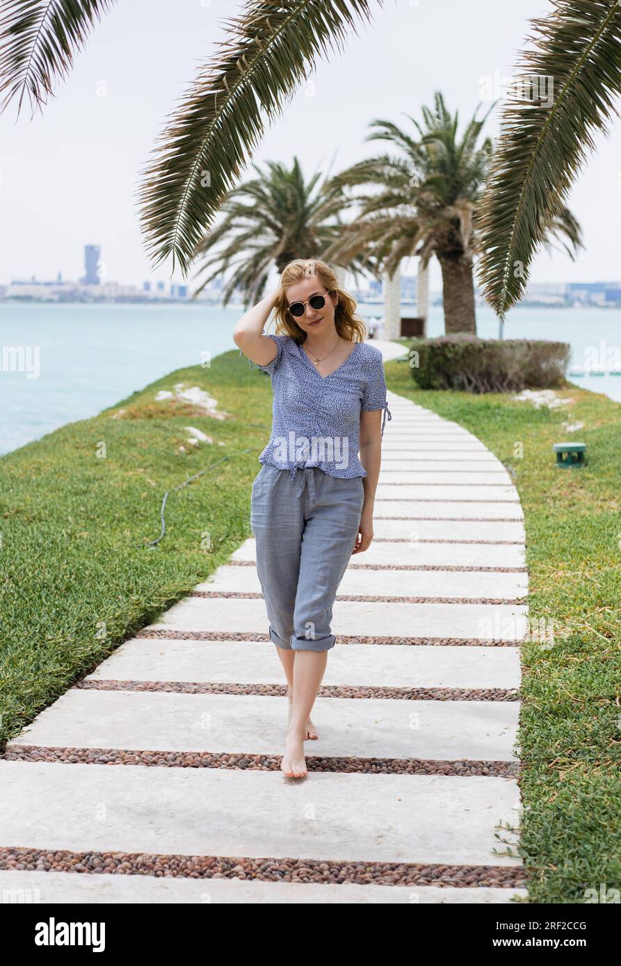 Young blond woman walking barefoot along path Stock Photo