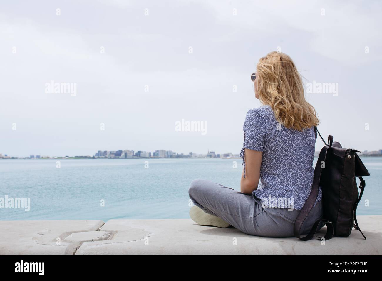 Backview of a blond woman sitting and watching the sea Stock Photo