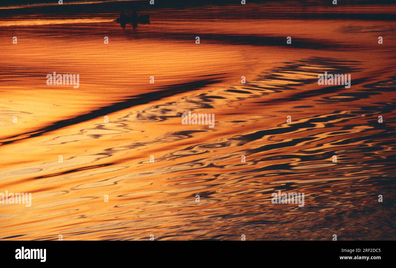 Wellen auf der Wolga im Sonnenuntergang, oben die Silhouette eines Fischerbootes * Volga waves with a fishing boat at Sunset Stock Photo