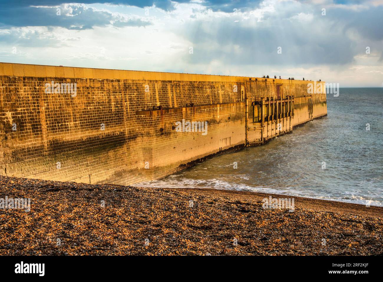 Golden sunset looking out to sea Folkestone Harbour Arm Pier Stock Photo