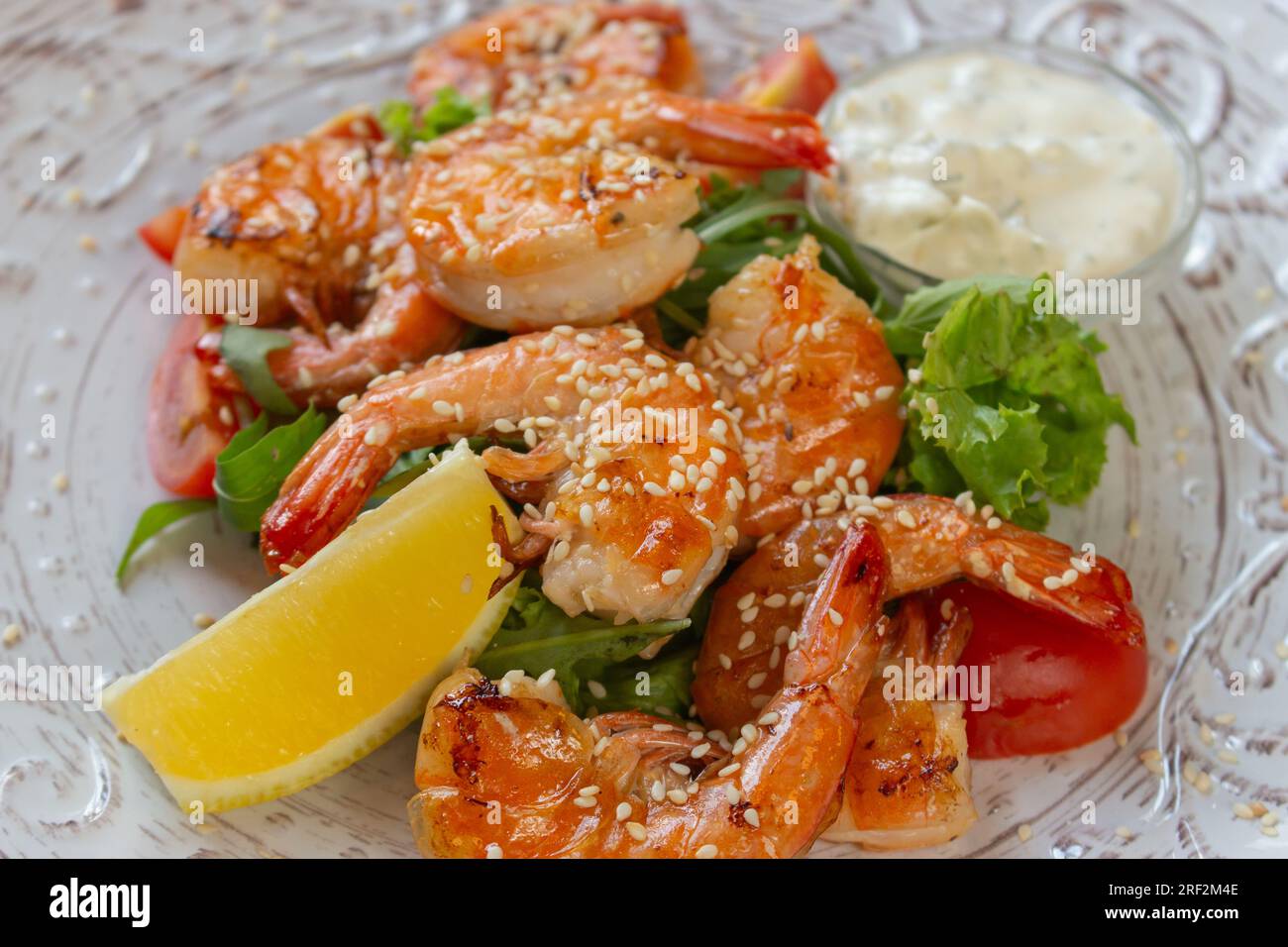 Shrimps with lemon and salad. Seafood close up. Served fish dish. Fish restaurant menu. Fried prawns with lemon. Mediterranean mollusk plate. Stock Photo