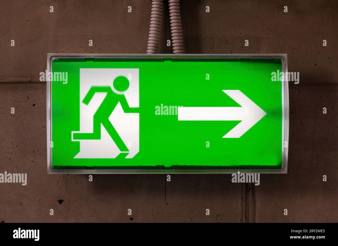 Green emergency exit sign on the concrete wall Stock Photo - Alamy