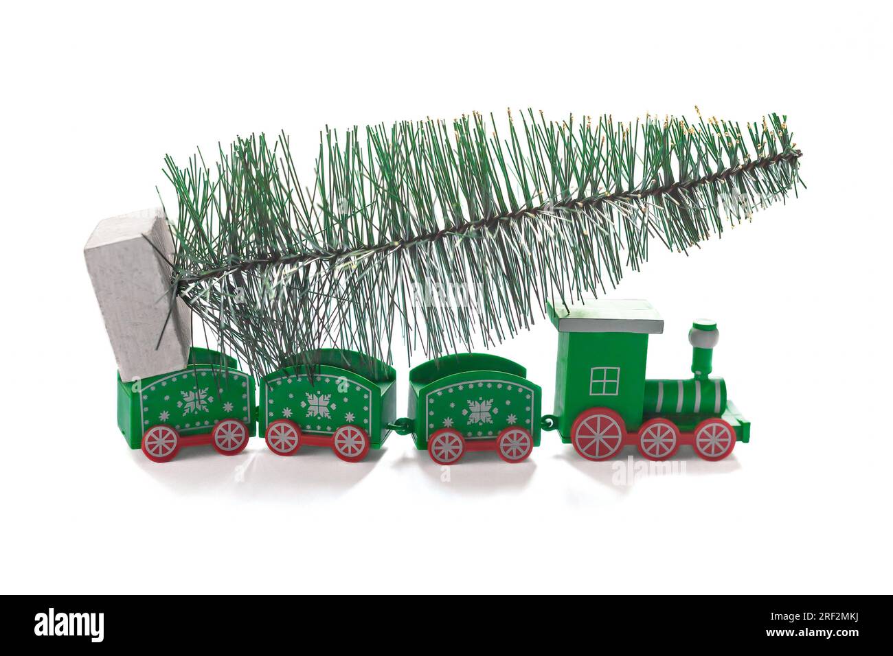 Figurine Toy Christmas train in green color carries a Christmas tree on a white background, an image for a decorative concept of the Christmas holiday Stock Photo