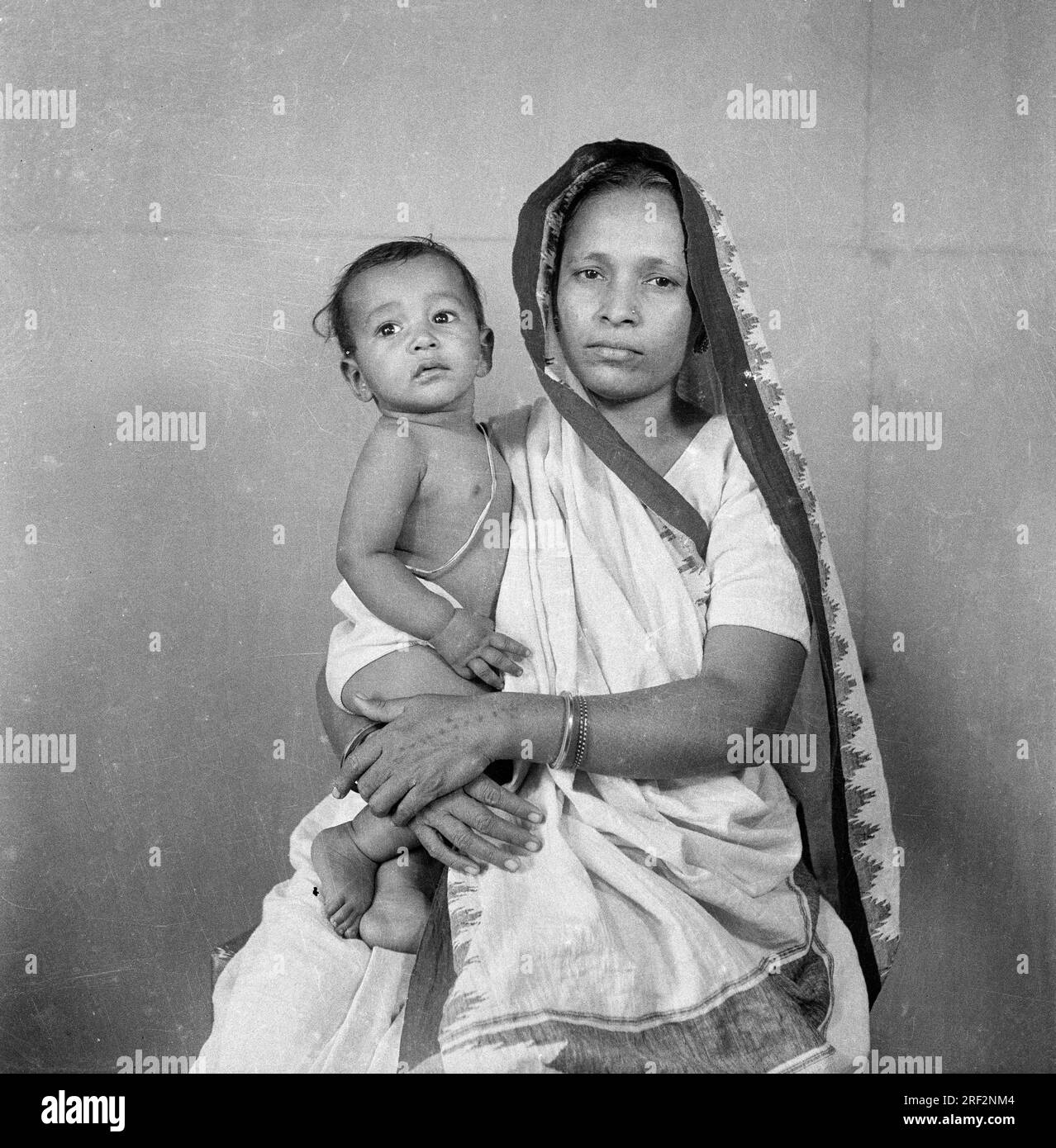 old vintage black and white 1900s picture of Indian mother child studio portrait wearing saree sacred thread India 1940s Stock Photo