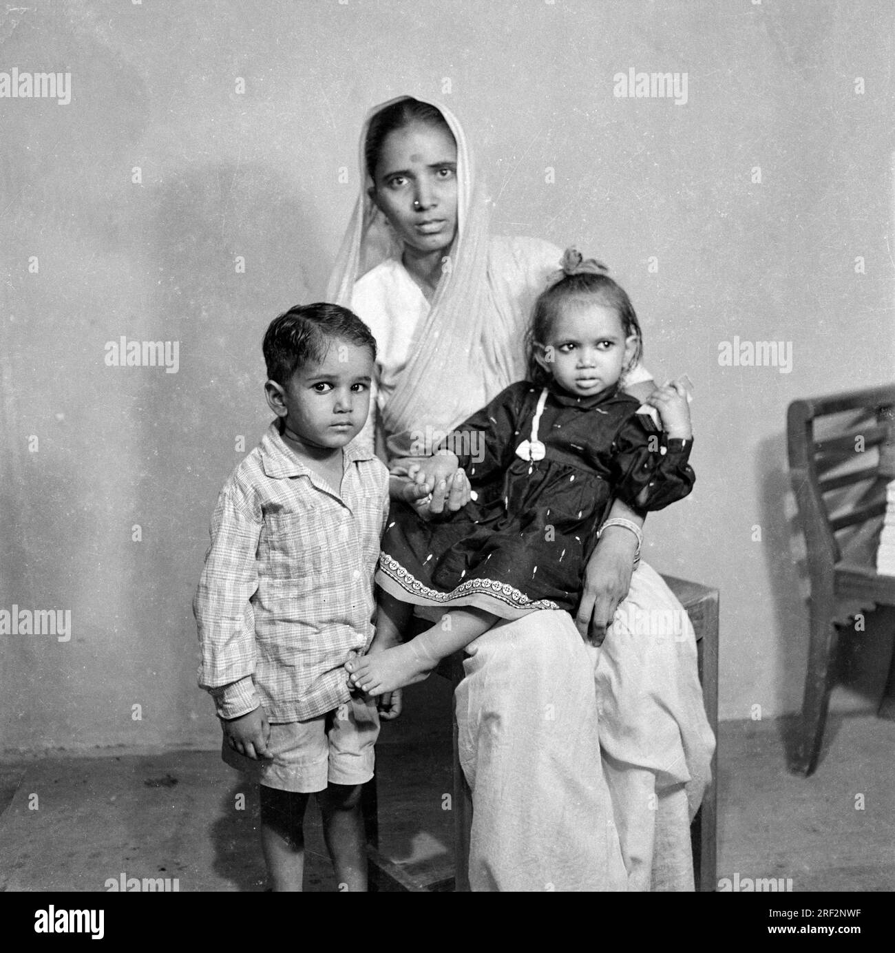 old vintage 1900s black and white picture of Indian family studio portrait woman sitting wearing sari son daughter India 1940s Stock Photo