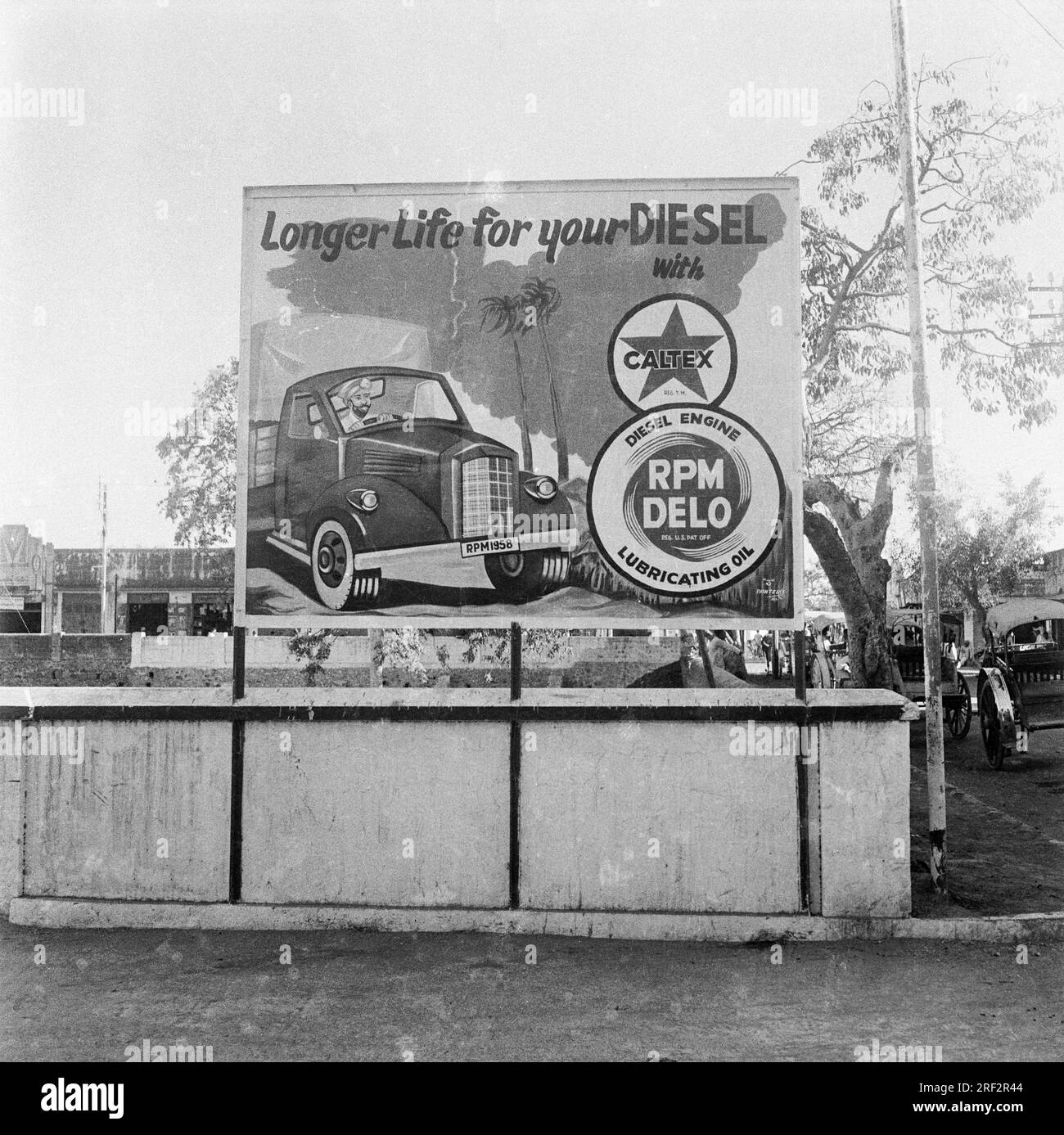 old vintage 1900s black and white picture of Caltex hoarding Longer Life for your Diesel RPM Delo lubricating oil India Stock Photo