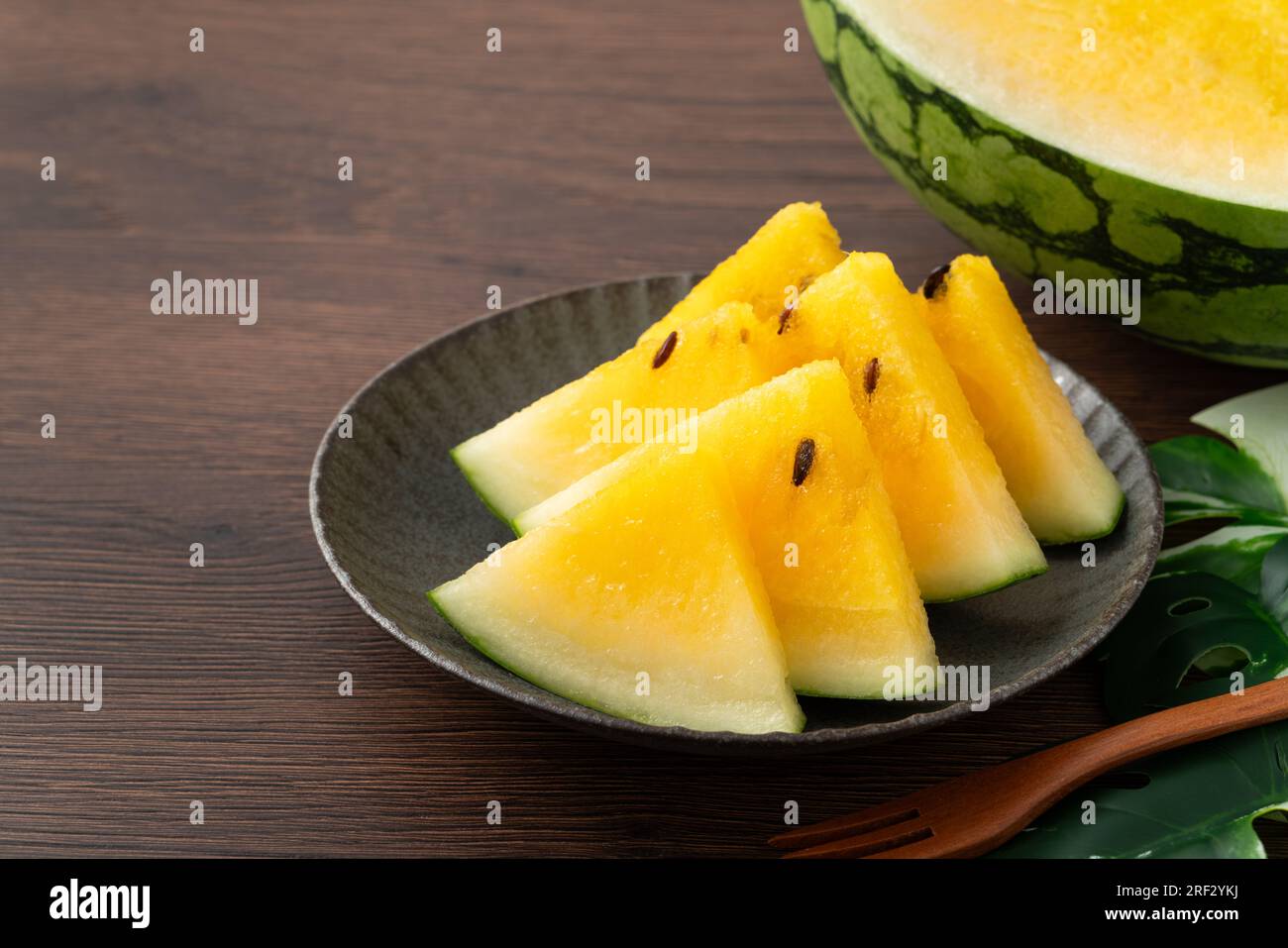 Sliced yellow golden watermelon in a plate on wooden table background ready for eating. Stock Photo