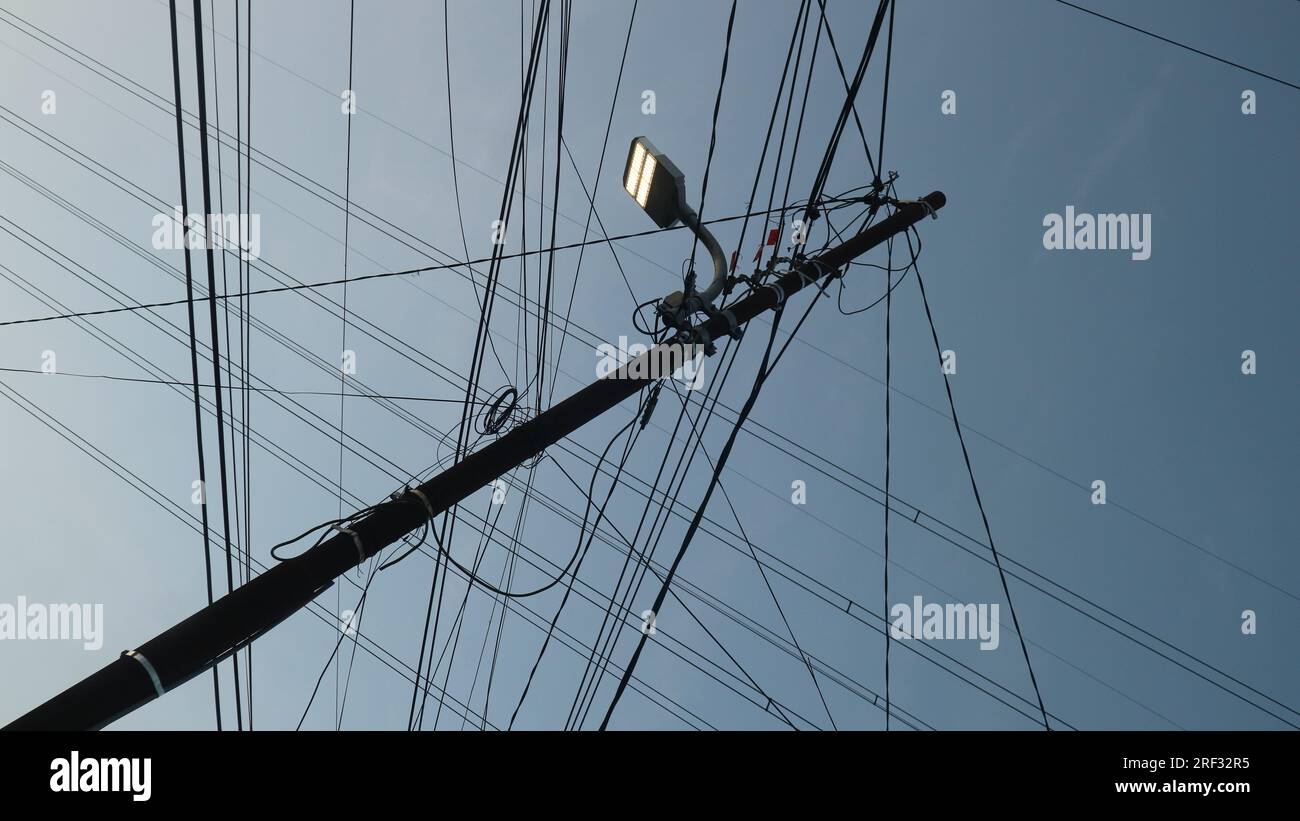 Electric poles and cables seen from below against the sky Stock Photo