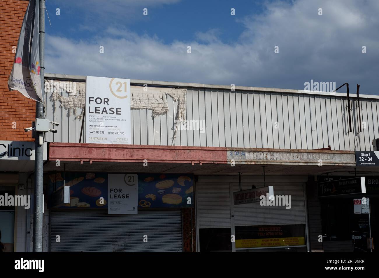 For Lease sign on the awning of a commercial property. Shutters down on a closed bakery shop