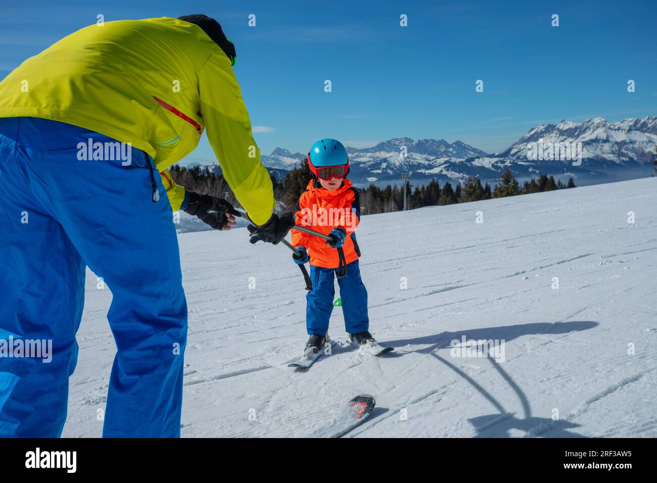 Father teach little boy child to ski move holding poles together Stock Photo
